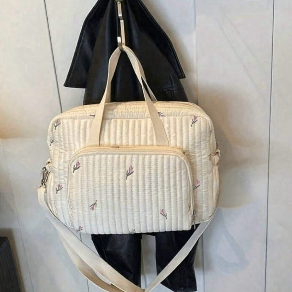 Sac à langer matelassé écru à motif floral délicat.