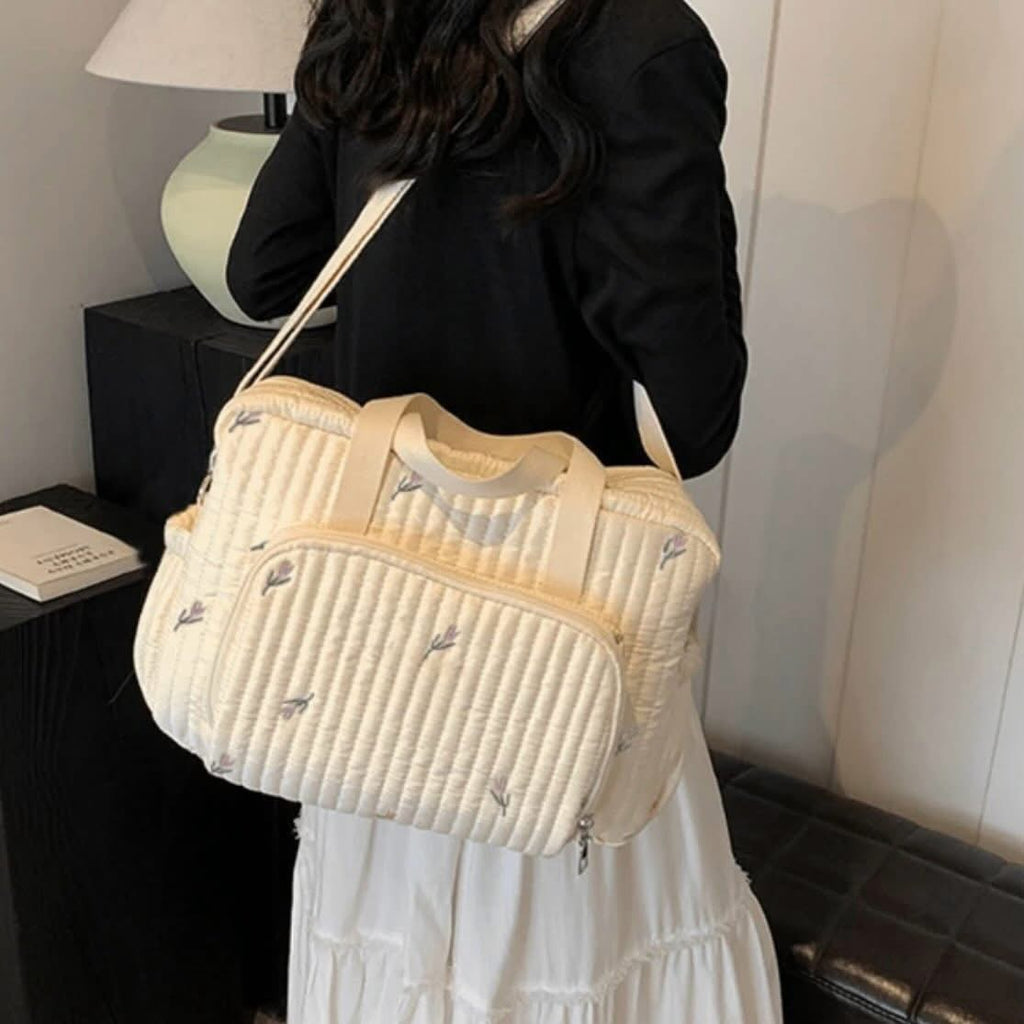 Sac à langer matelassé écru à motif floral délicat.