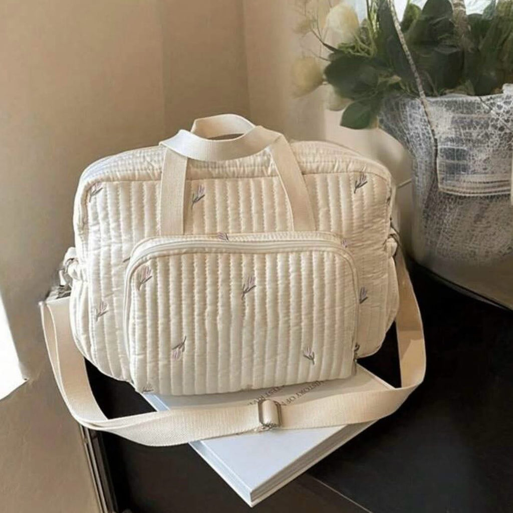 Sac à langer matelassé écru à motif floral délicat.